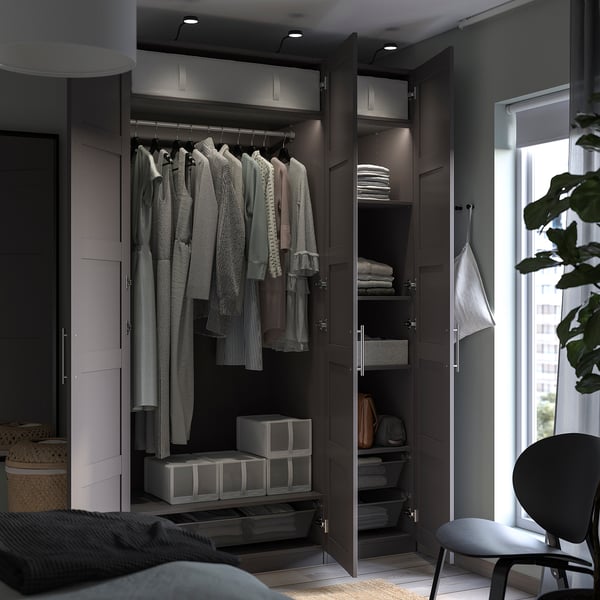 Open dark brown PAX wardrobe displaying clothes, folded items, and accessories.