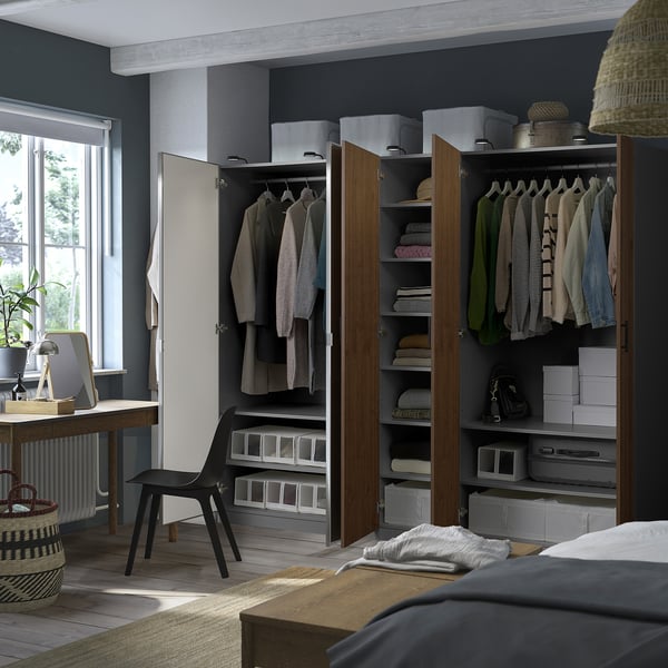 Bedroom with gray PAX wardrobes showing organized clothes, shelves, and boxes. One door open revealing hanging garments and folded items.