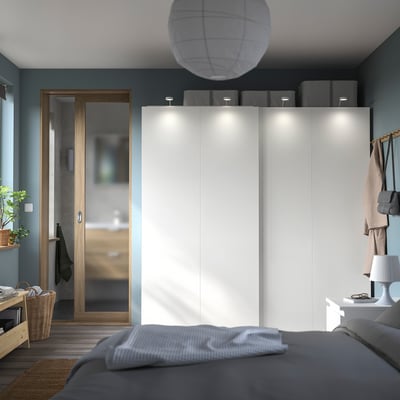Modern bedroom with a white PAX wardrobe, grey bedding, and wooden accent door.