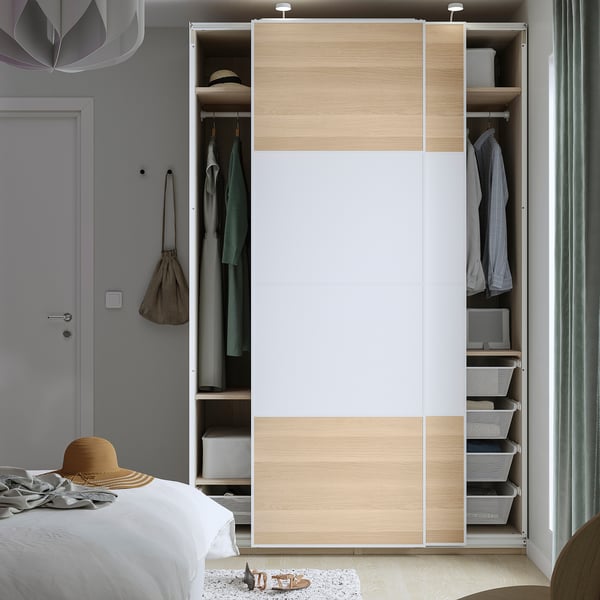 Modern wardrobe with adjustable feet, sliding doors, and interior baskets for organized clothing storage.
