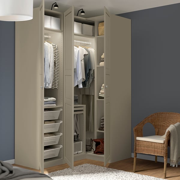 Open beige PAX wardrobe with clothes, shelves, and storage bins, lit from inside.