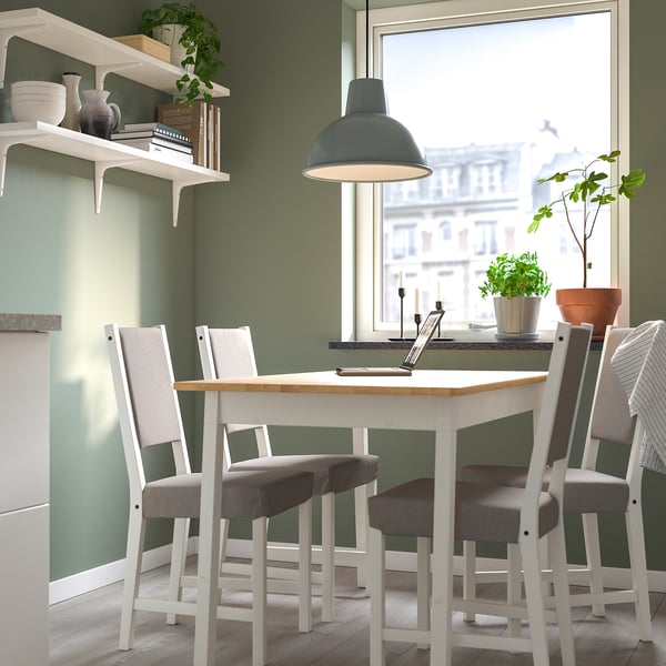 Small cozy dining setup with white table and grey chairs, decorated with green plants, under a blue pendant light.
