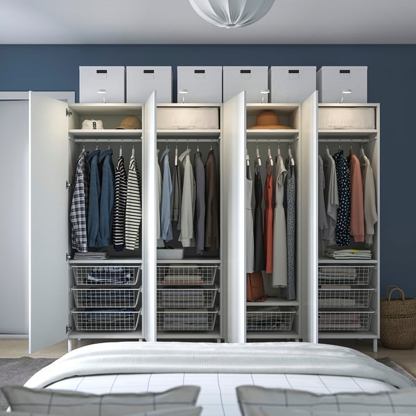 Open wardrobe with clothes, storage baskets, and boxes. Mounted against a blue wall, positioned above a bed.