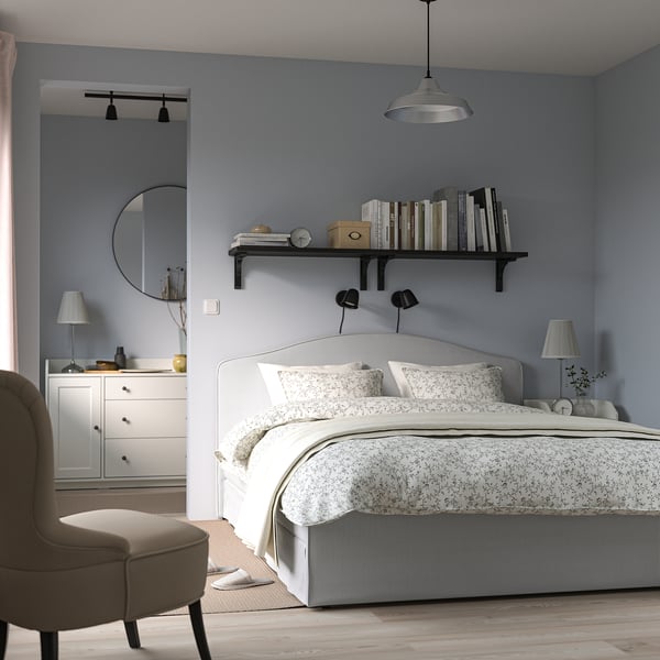 Modern cozy bedroom with RAMNEFJÄLL upholstered bed, bookshelf, armchair, dresser, and lamp.