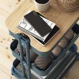 A multilevel cart with a wooden lid holds a tablet, remote, and notebook, showing its use for organizing and storing items.