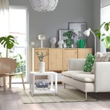 Modern living room with light gray sofa, wooden cabinet, and off-white rug with green checks, smaller than the sofa.