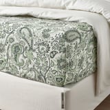 Neat bed with green paisley sheet, smooth texture.