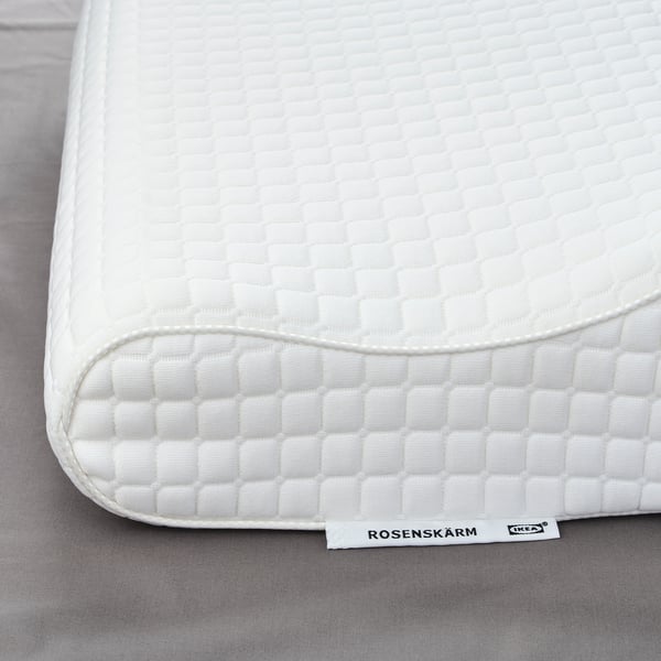 White pillow with textured cover, ROSENSKÄRM label visible, lying on flat surface.