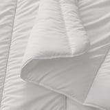 A close-up of a soft, white duvet with smooth fabric and even stitching, emphasizing its high-quality texture and fluffy appearance.
