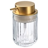 A SILVTJÄRN soap dispenser with a gold-colored brass pump, clear glass body, and modern design.