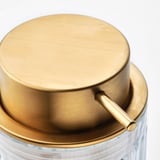 Gold-tinted soap dispenser top with handle on clear glass base. Modern design, high-quality materials.