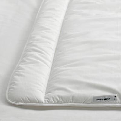 A close-up of a white, fluffy comforter with neat stitching and a tag on one corner, indicating high quality and craftsmanship.
