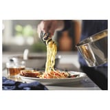 Person cooking spaghetti in pots; kitchen setting.
