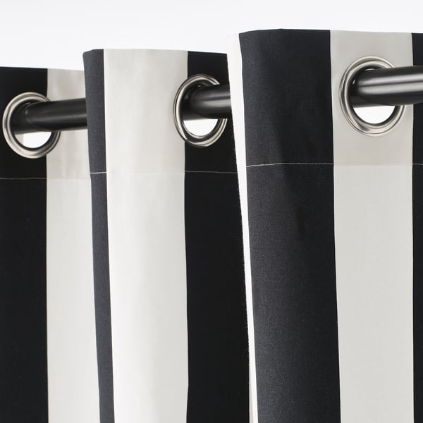 Black and white striped curtains hang with silver eyelets, creating a modern drape.