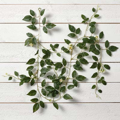Artificial leafy plant decoration with green leaves and white flowers, suitable for indoor and outdoor use.