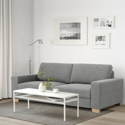 Minimalist living room with gray sofa, white table, wall art, lamp & photos.