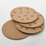 Four round cork coasters with polka dot patterns stacked neatly. Soft, natural, and reversible design.