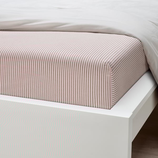 A neatly made bed with a striped fitted sheet, showing crisp lines and quality cotton material on a white bed frame.