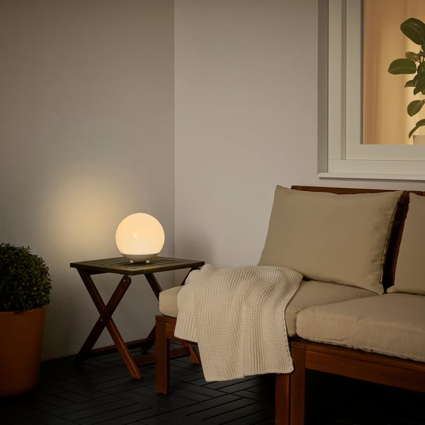 SOLVINDEN solar light on wood table with bench and plant.