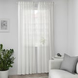 SOTSTÄVMAL white curtains, sheer, wave pattern, 100% recycled polyester, floor-length, central window, slim plant, gray pillow.