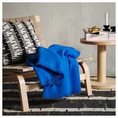 Bright blue wool blanket folded neatly, soft feel, rectangular shape, clean lines, scandinavian design.
