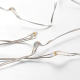 Close-up of decorative, bendable string lights with tiny glowing bulbs on a bright white background.