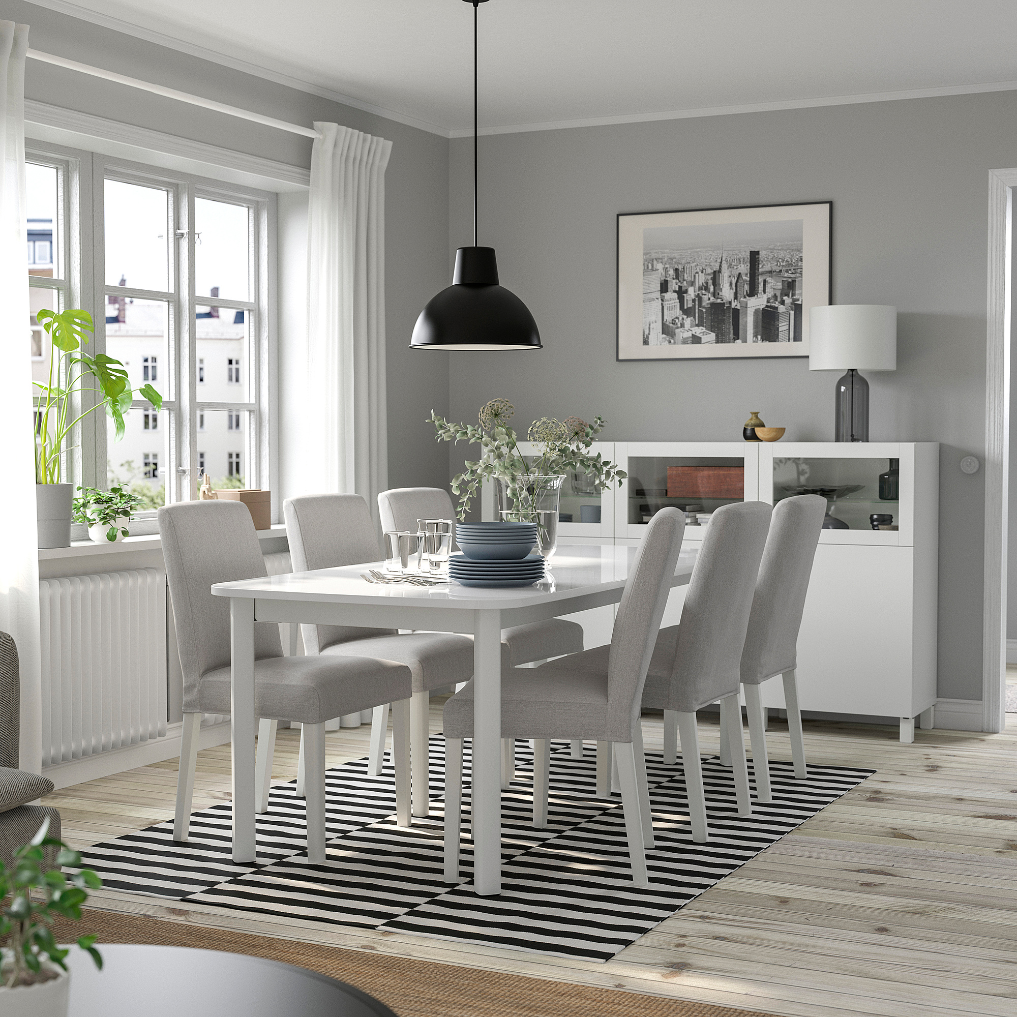 Modern dining area with extendable table for six, black lamp, striped rug, city view window.