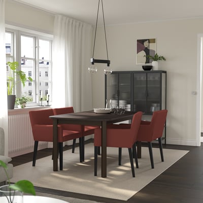 Modern dining room with STRANDTORP table, red chairs, and cabinet. Seats up to 8. Dark wood, metal base, minimalist decor.