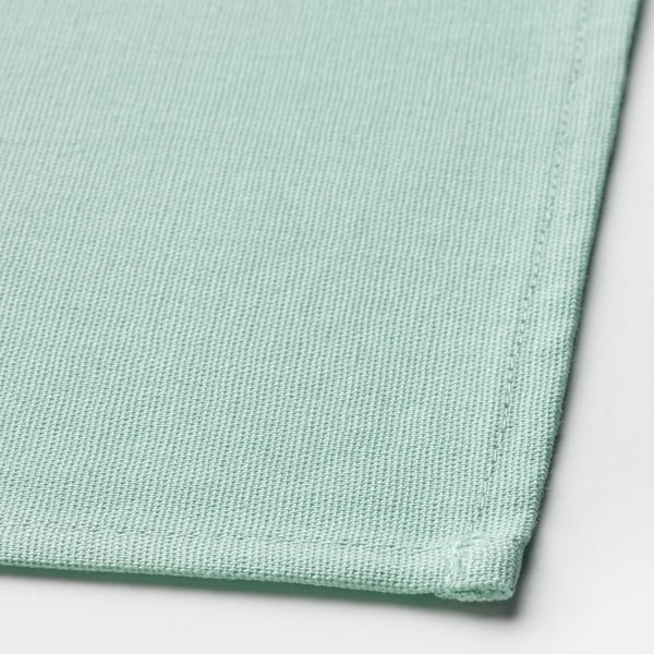Light green woven cotton napkin, neatly folded. High-quality texture visible.