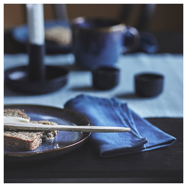 SVARTSENAP blue napkins on black table, with wooden knife, dark background, texture detail.