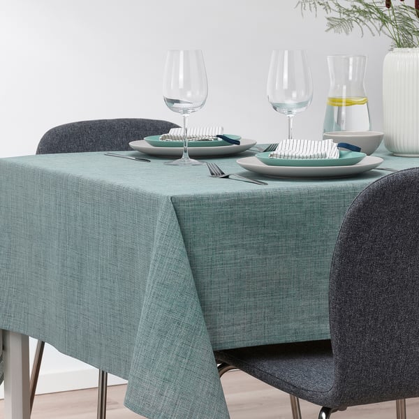 Table set with green-blue cotton tablecloth, plates, glasses, cutlery, vase with greenery. Suitable for 4-6 people.