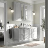A modern gray TÄNNFORSEN bathroom cabinet with a marble countertop, sink, and mirrored cabinets, fitting neatly within the bathroom space.