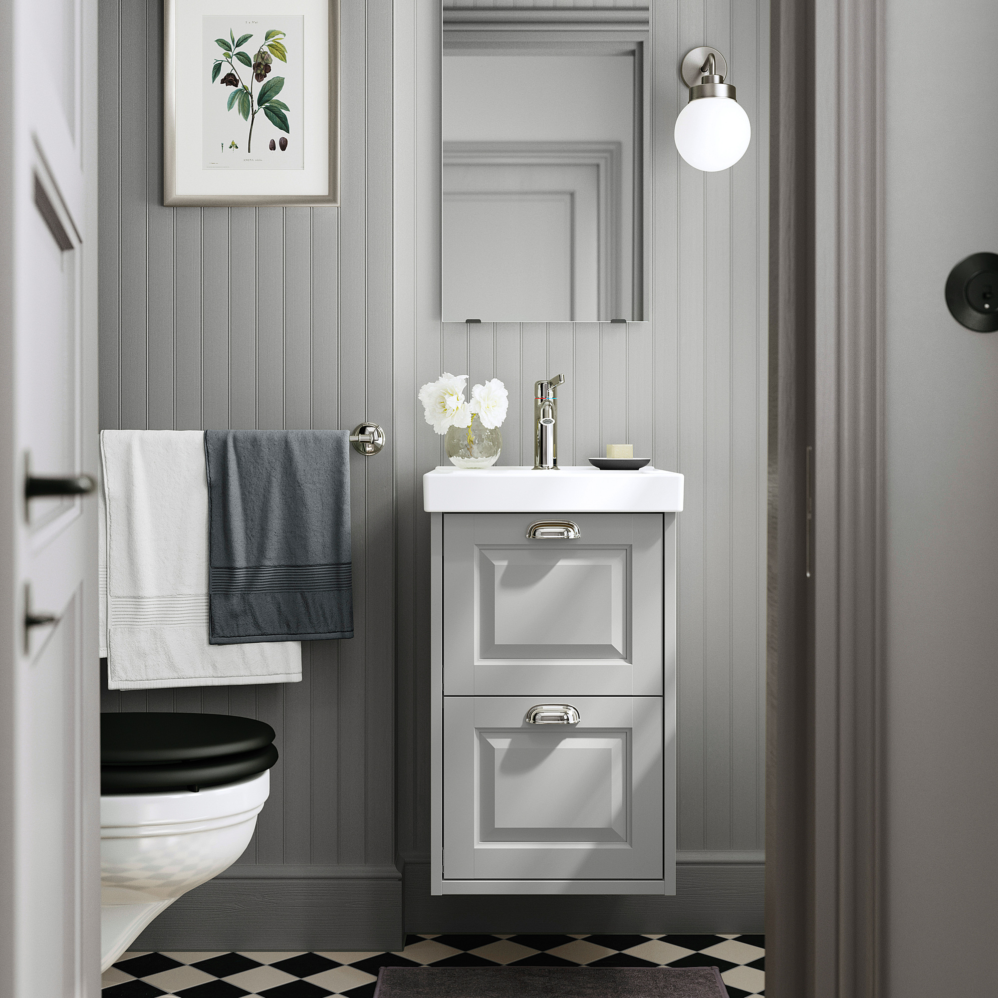 Modern gray bathroom with white sink cabinet, beveled edges, wall-mounted, with black toilet, checkered floor, gray towels, and round mirror.