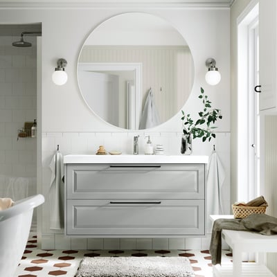 Gray bathroom vanity with mirror, lights & plants.