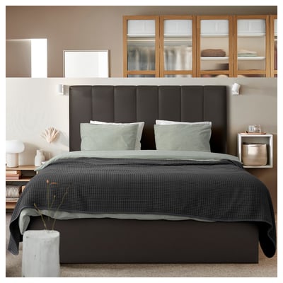 Modern bedroom with black TJÅLLE headboard, gray bedding, and wooden shelves.