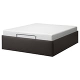 A TJÅLLE bed frame in black with a white mattress. It boasts a modern design with clean lines and offers hidden storage underneath.