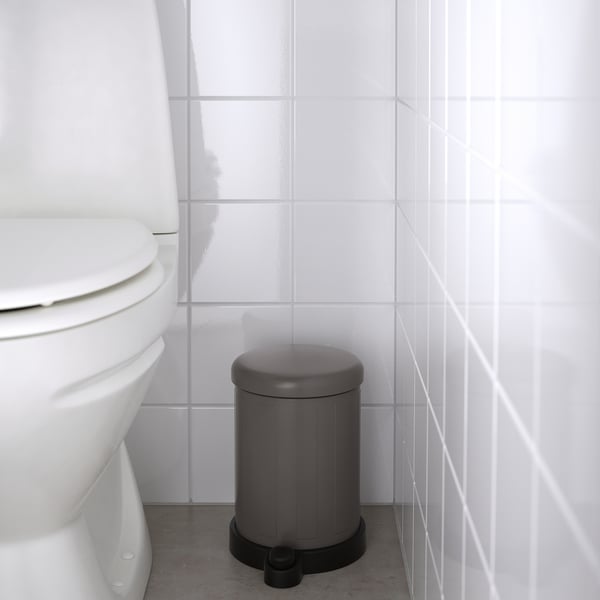 Gray TOFTAN bin with soft-close lid, next to toilet, easy to move & clean.