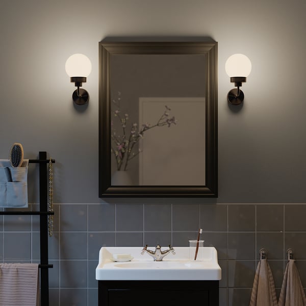 Modern bathroom with TOFTBYN mirror, wall lamps, sink, toothbrushes, and toiletries.