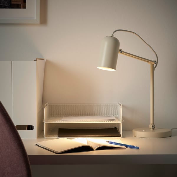 White adjustable TOLFT desk lamp, ideal for reading, with small book and pen.
