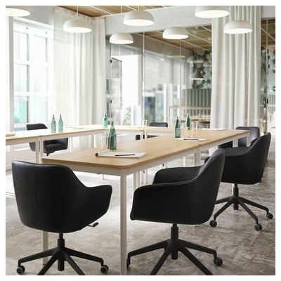 Modern office with four TOSSBERG chairs around wooden table with drinks, large windows.