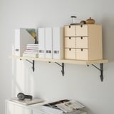 Wooden wall shelf holding boxes and books, with a light wood finish and black metal brackets. Display items include headphones and a vase.
