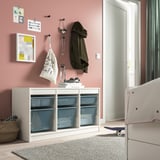 TROFAST: white storage unit with blue mesh boxes. Wall-mounted hooks, rug, and skateboard.