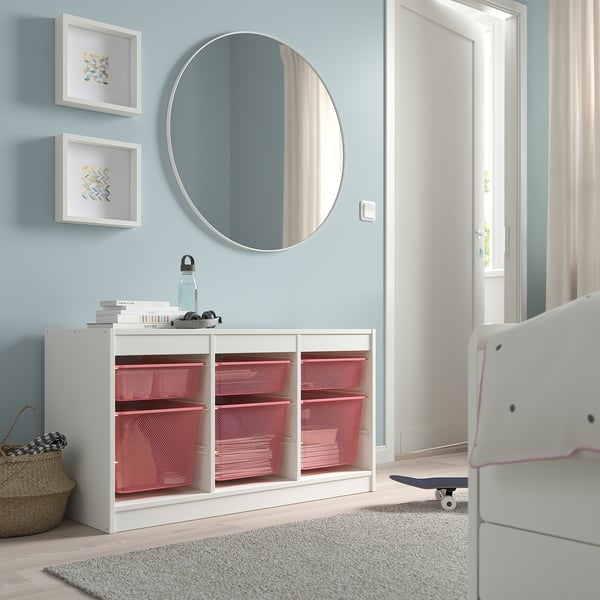 White TROFAST unit with pink drawers, blue wall, mirror, skateboard.