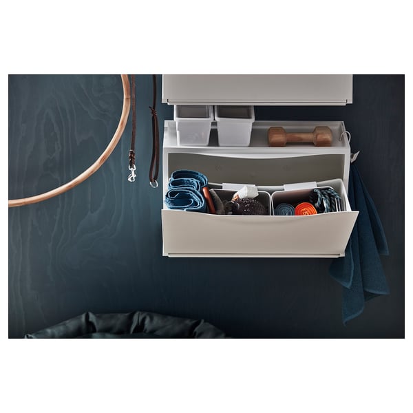 Ikea TRONES white shallow storage cabinet with various items stored inside, wall-mounted.