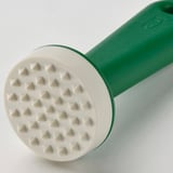 Close-up of green kitchen tool with white textured head for tenderizing meat or vegetables.