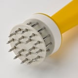 Stainless steel tenderizer spikes on white tool with yellow handle, suggesting high-quality design and durability.