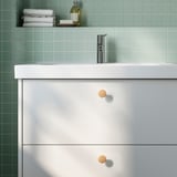 Modern bathroom with white sink cabinet & green tiles.