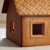 Mini gingerbread house model, brown, textured roof, square windows.