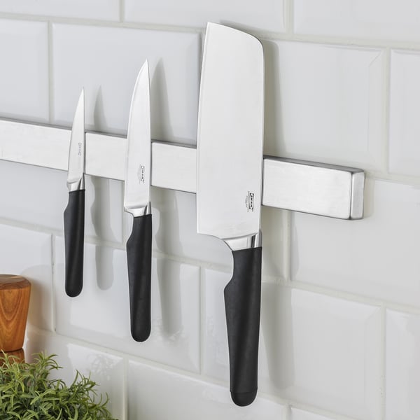 Knife rack on tiled wall holding multiple knives with black handles; knives labeled VÖRDA.