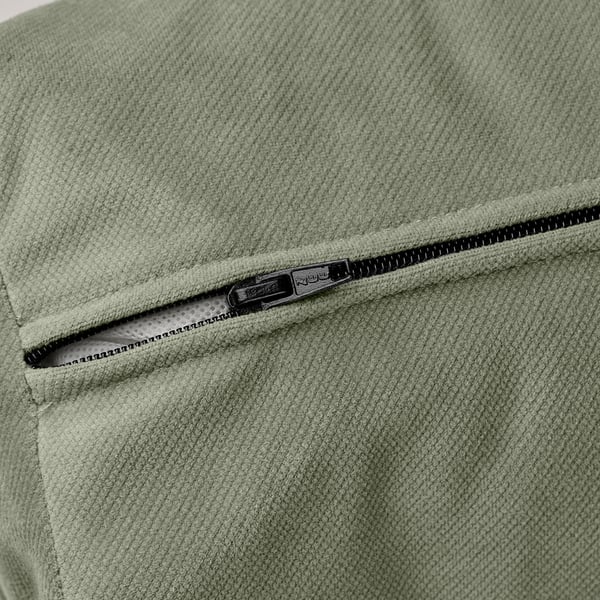 Close-up of light green sofa-bed zipper, highlighting smooth fabric and quality zipper pull.